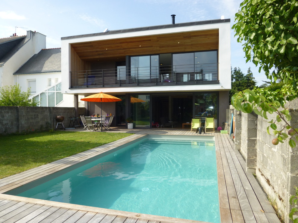 Imagen de piscina actual de tamaño medio rectangular en patio trasero con entablado