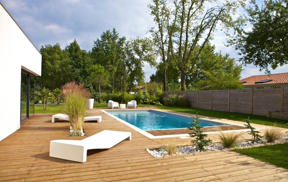 Réalisation d'une piscine design rectangle avec une terrasse en bois.