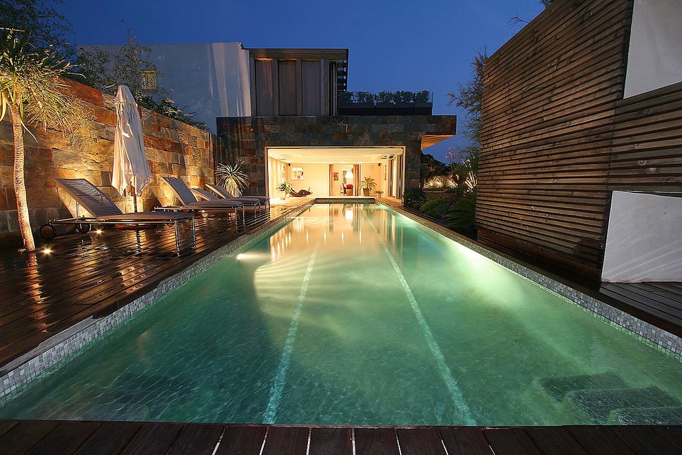 Modelo de piscina alargada actual grande rectangular en patio delantero con entablado