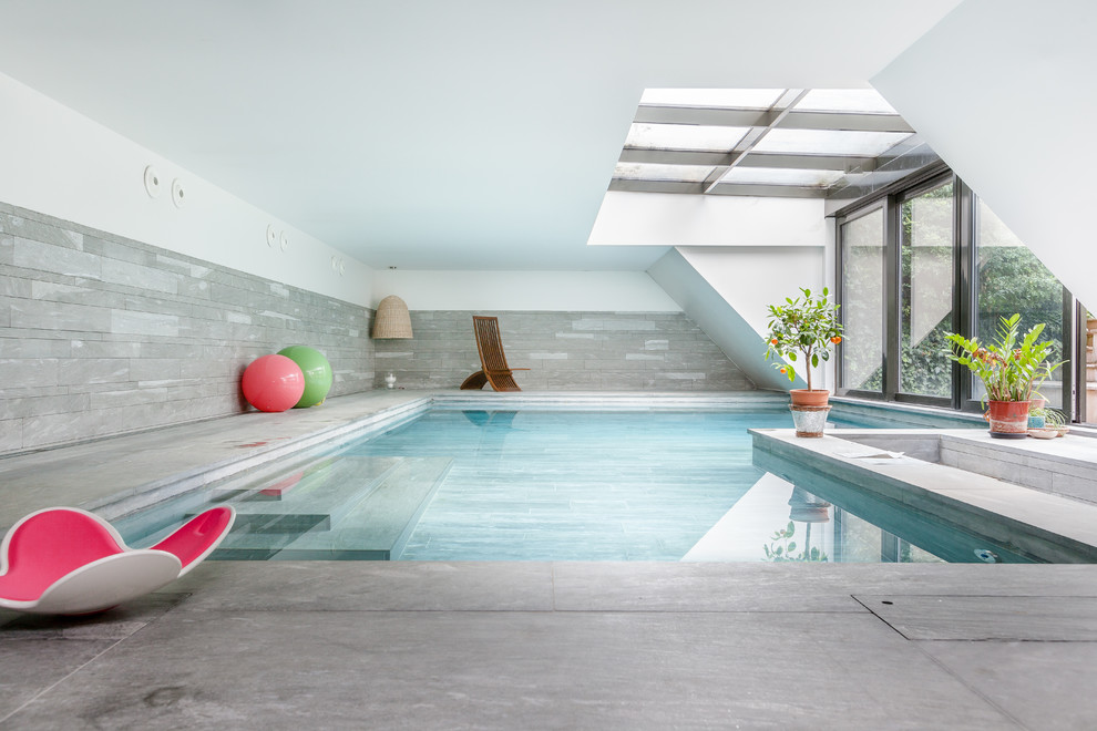 Idée de décoration pour une grande piscine intérieure design en L avec une dalle de béton.