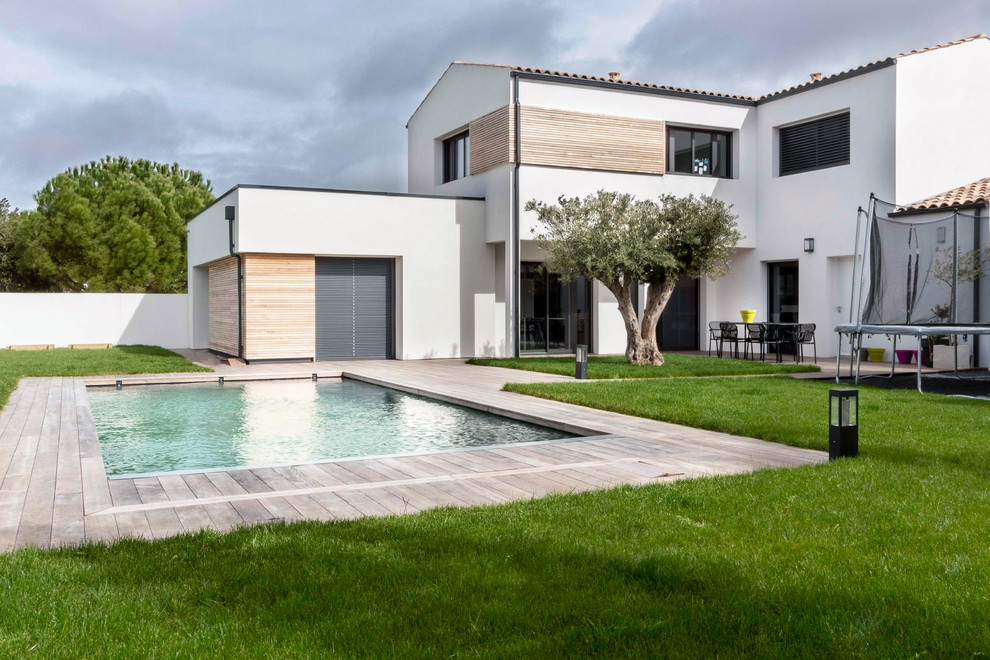 Exemple d'une piscine arrière tendance rectangle avec une terrasse en bois.