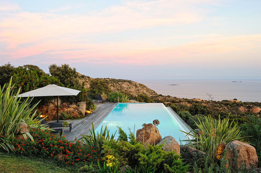 Photo of a large contemporary rectangular infinity swimming pool in Marseille with decking and a water feature.