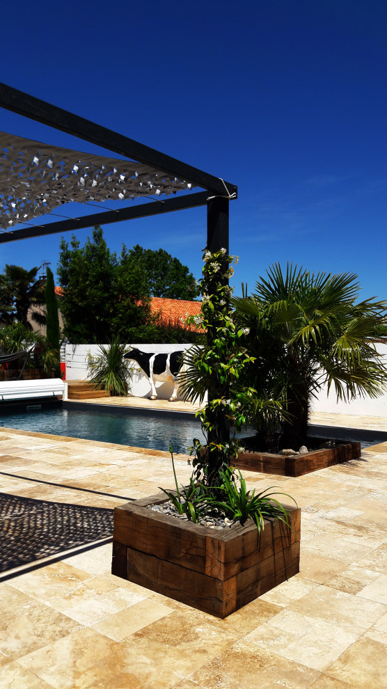 Diseño de piscina mediterránea pequeña en forma de L en patio trasero con paisajismo de piscina y adoquines de piedra natural