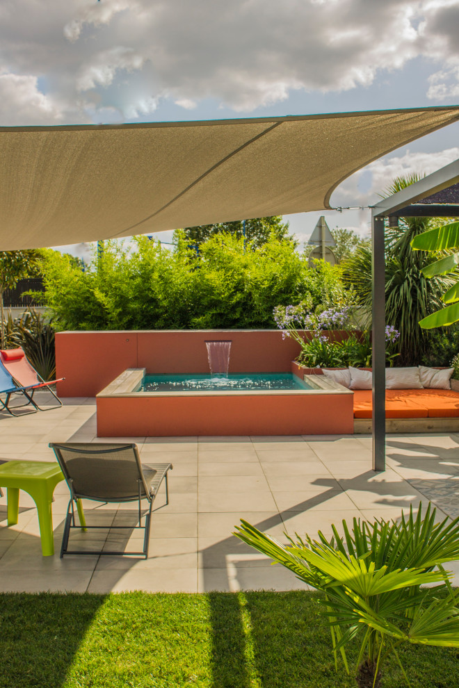 Ejemplo de piscina tropical pequeña rectangular en patio trasero con suelo de baldosas