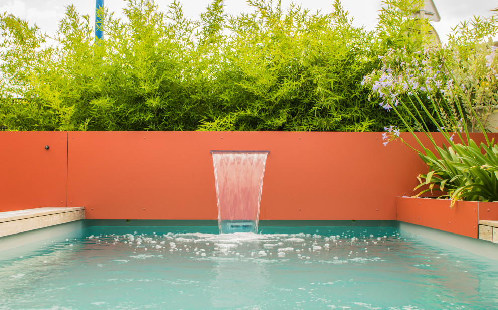 Diseño de piscina tropical pequeña rectangular en patio trasero con entablado