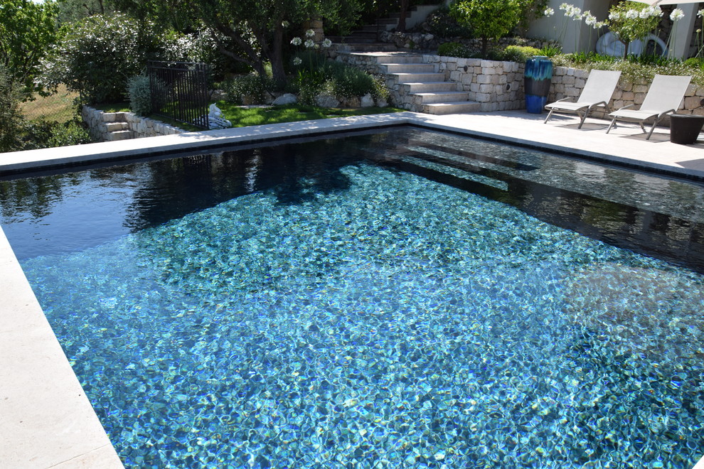 Ejemplo de piscina infinita actual pequeña rectangular en patio delantero con adoquines de piedra natural