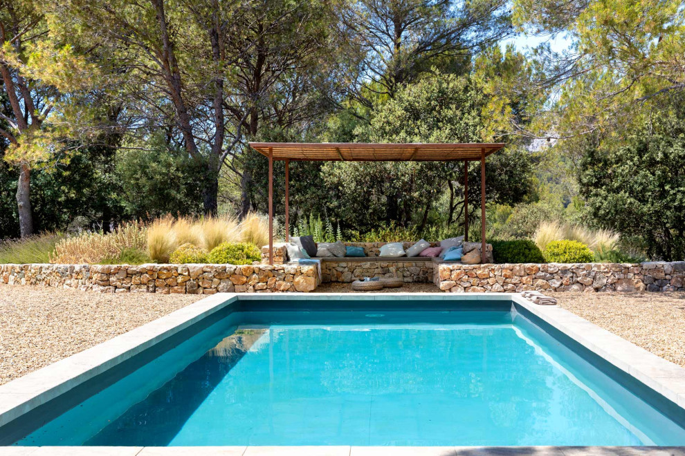 Foto de piscina mediterránea grande rectangular en patio trasero con gravilla