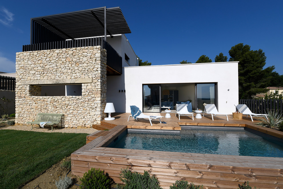 Réalisation d'une grande piscine à débordement et avant méditerranéenne rectangle avec une terrasse en bois.