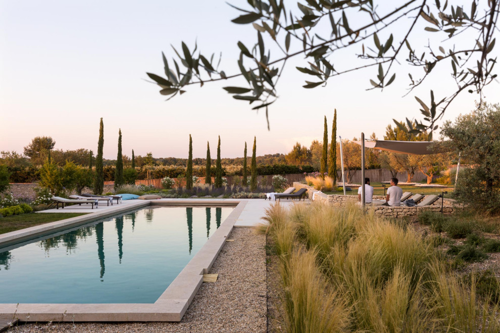Idée de décoration pour un grand piscine avec aménagement paysager arrière méditerranéen rectangle avec du gravier.