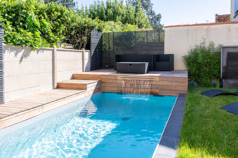 Diseño de piscina con fuente moderna pequeña rectangular en patio trasero con entablado
