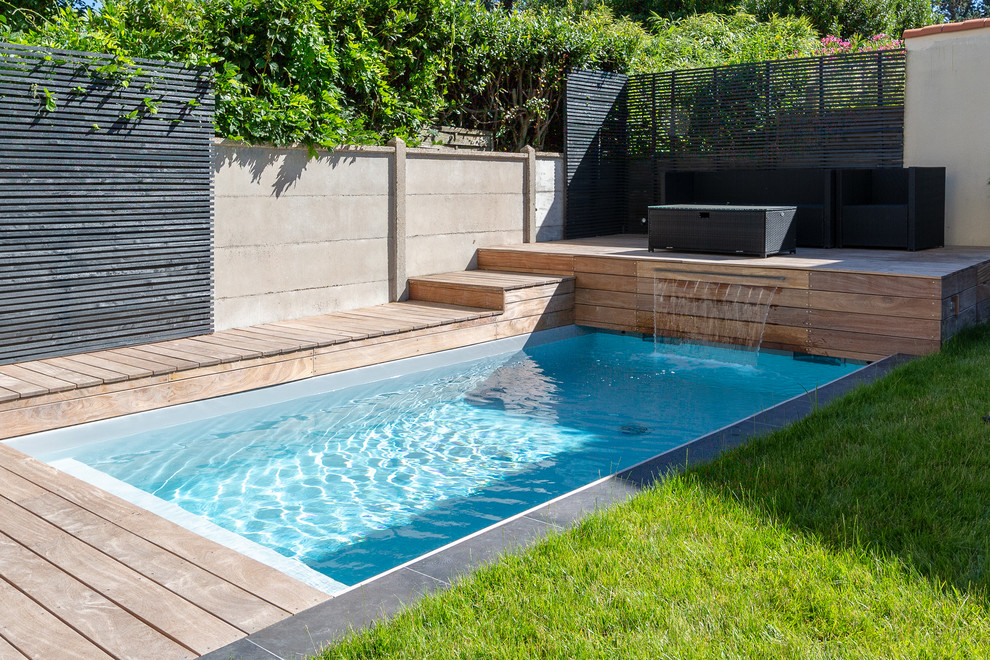Modelo de piscina con fuente minimalista pequeña rectangular en patio trasero con entablado