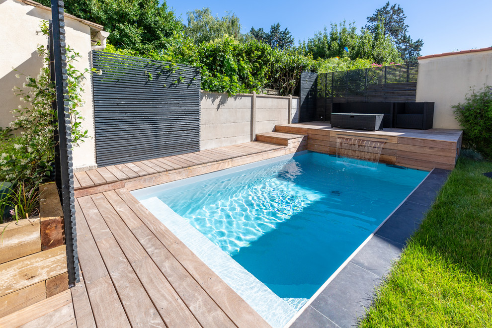 На фото: маленький прямоугольный бассейн на заднем дворе в стиле модернизм с фонтаном и настилом для на участке и в саду с