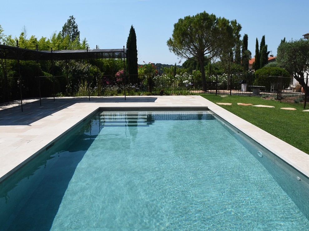 На фото: большой прямоугольный бассейн в средиземноморском стиле с покрытием из каменной брусчатки с