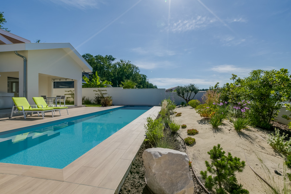 Esempio di una piscina monocorsia costiera rettangolare di medie dimensioni e davanti casa con paesaggistica bordo piscina e piastrelle