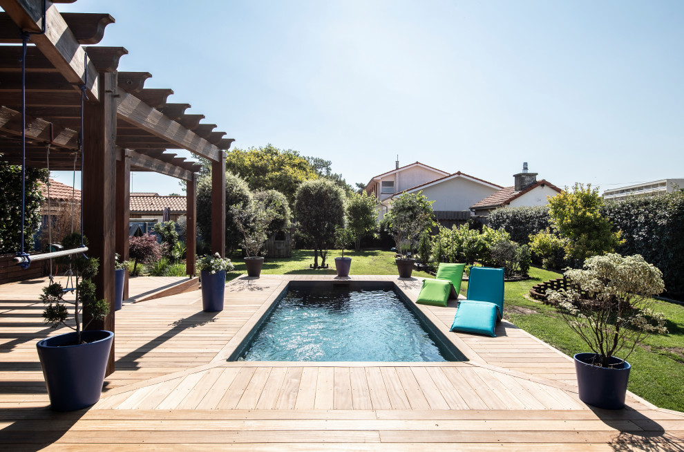 Modelo de piscina mediterránea rectangular en patio trasero con entablado