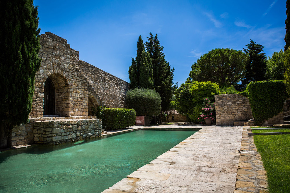 Imagen de piscina alargada clásica de tamaño medio rectangular en patio trasero con adoquines de piedra natural