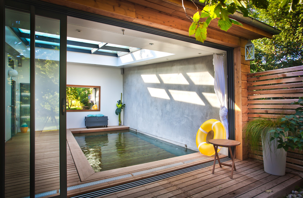 Cette photo montre une piscine intérieure tendance rectangle et de taille moyenne avec une terrasse en bois.
