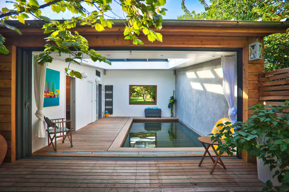 Cette image montre une piscine intérieure design de taille moyenne et rectangle avec une terrasse en bois.