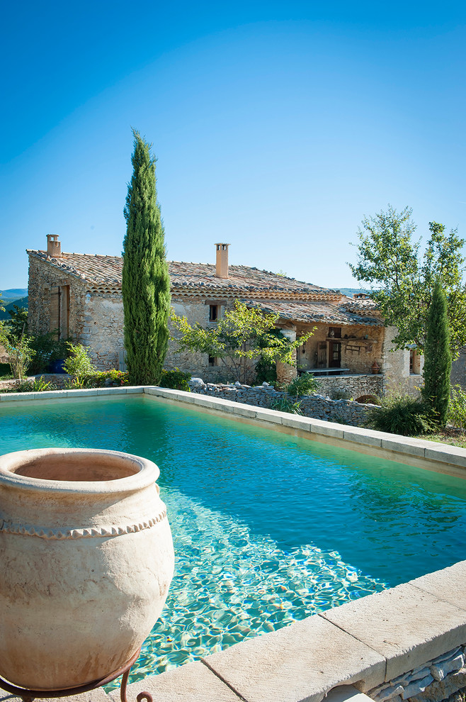 Cette photo montre une piscine arrière méditerranéenne de taille moyenne et rectangle avec des pavés en pierre naturelle.