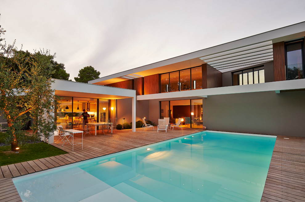 Exemple d'une grande piscine arrière tendance rectangle avec une terrasse en bois.