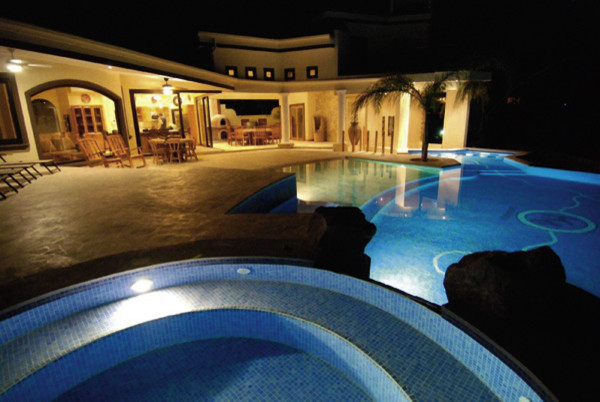 На фото: огромный естественный бассейн произвольной формы в морском стиле с джакузи и покрытием из бетонных плит