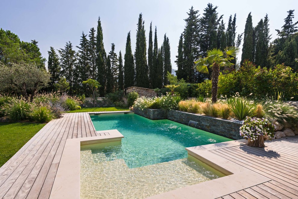 Ejemplo de piscina con fuente alargada contemporánea a medida en patio trasero con entablado