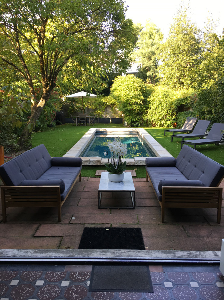 Imagen de piscina alargada tradicional renovada de tamaño medio rectangular en patio trasero con paisajismo de piscina y adoquines de piedra natural