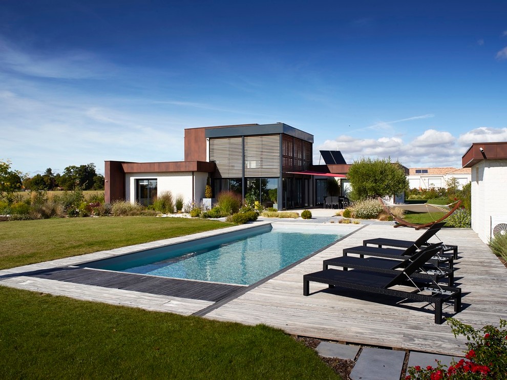 Foto de piscina alargada actual grande rectangular en patio trasero con entablado