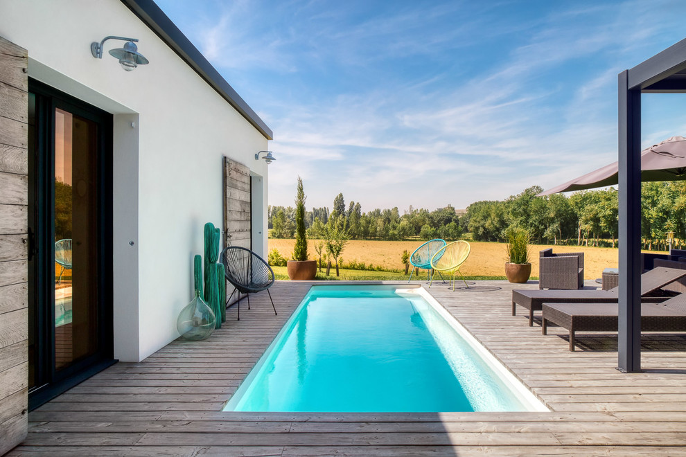 Diseño de piscina alargada contemporánea de tamaño medio rectangular en patio lateral con entablado