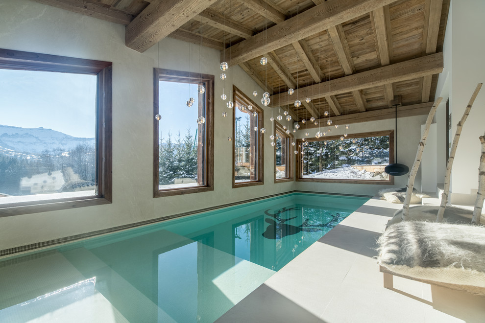 Large rustic indoor rectangular lengths swimming pool in Lyon with tiled flooring.