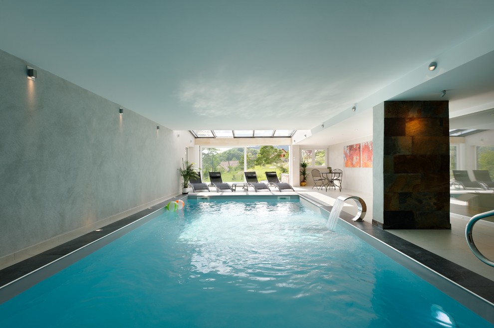 Idée de décoration pour une grande piscine intérieure design rectangle avec un point d'eau et une dalle de béton.