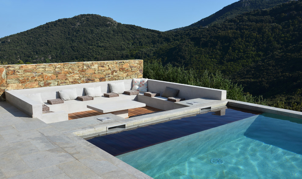 Medium sized contemporary back rectangular swimming pool in Corsica with natural stone paving.