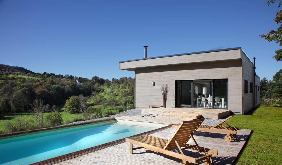 Diseño de piscina alargada contemporánea grande rectangular en patio trasero con entablado