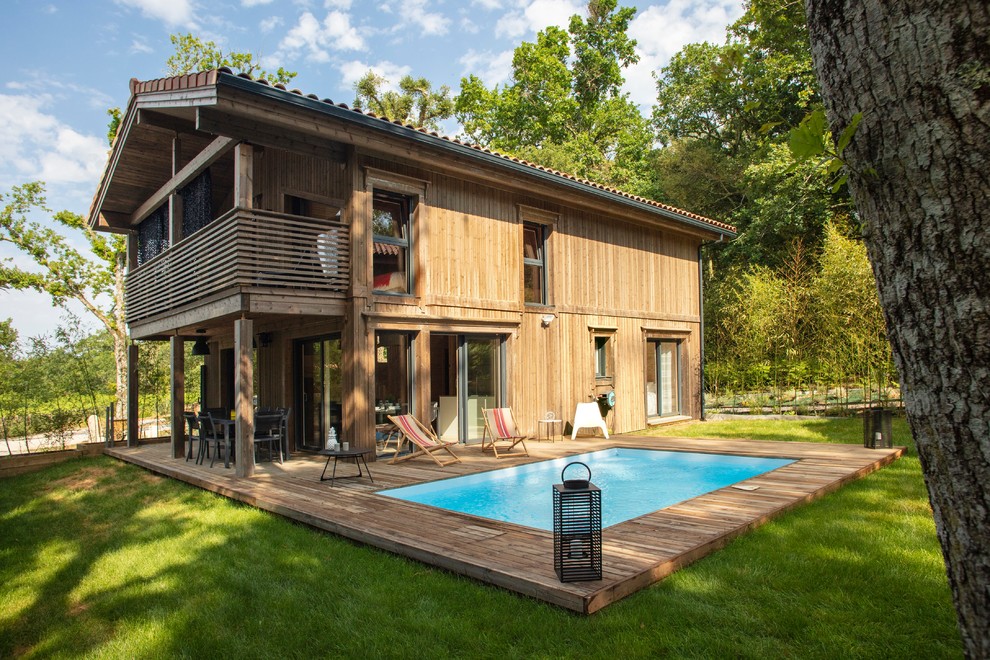 Cette photo montre une piscine arrière scandinave rectangle avec une terrasse en bois.