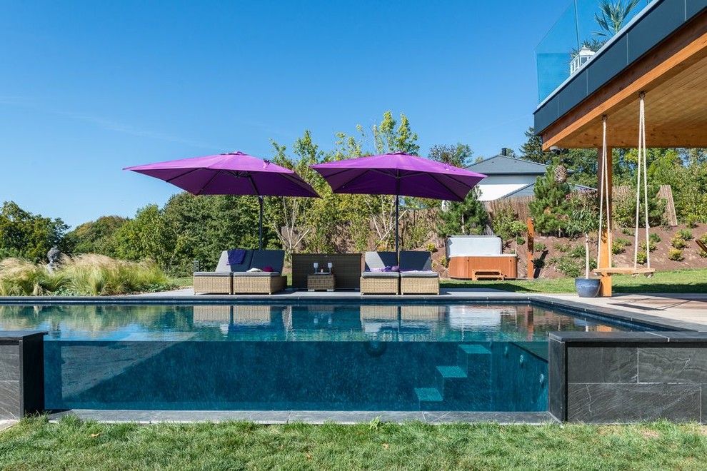 Esempio di una grande piscina a sfioro infinito minimal rettangolare davanti casa con pedane