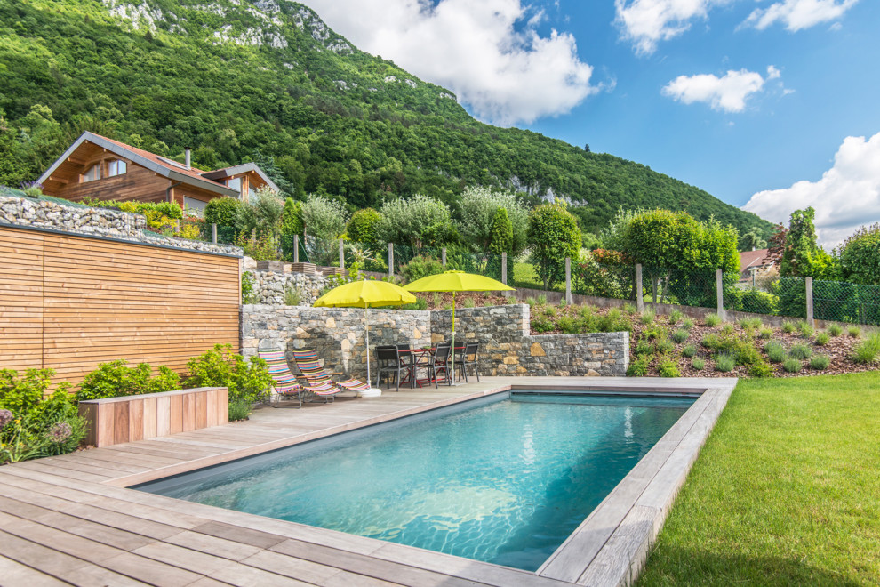 Aménagement d'une piscine arrière scandinave rectangle avec une terrasse en bois.