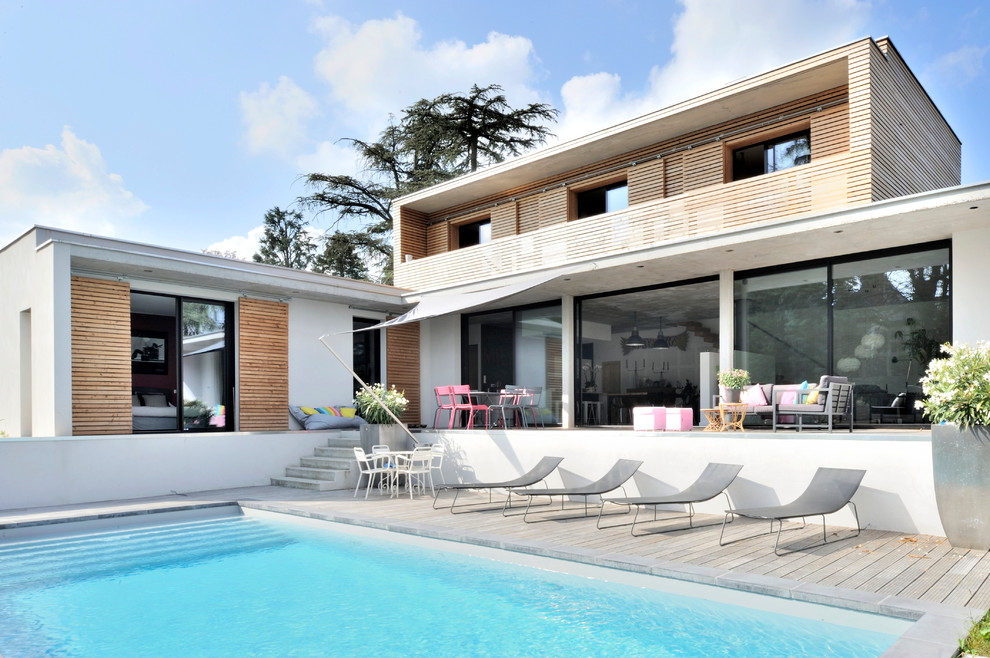 Réalisation d'une piscine arrière design rectangle et de taille moyenne avec une terrasse en bois.