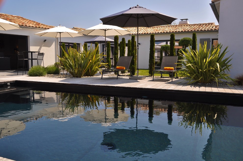 Aménagement d'une piscine arrière méditerranéenne rectangle et de taille moyenne avec une terrasse en bois.