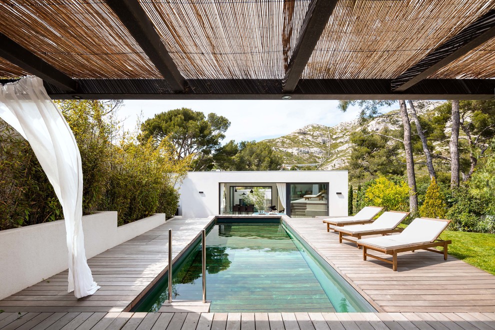 Modelo de piscina alargada contemporánea de tamaño medio rectangular en patio trasero con entablado