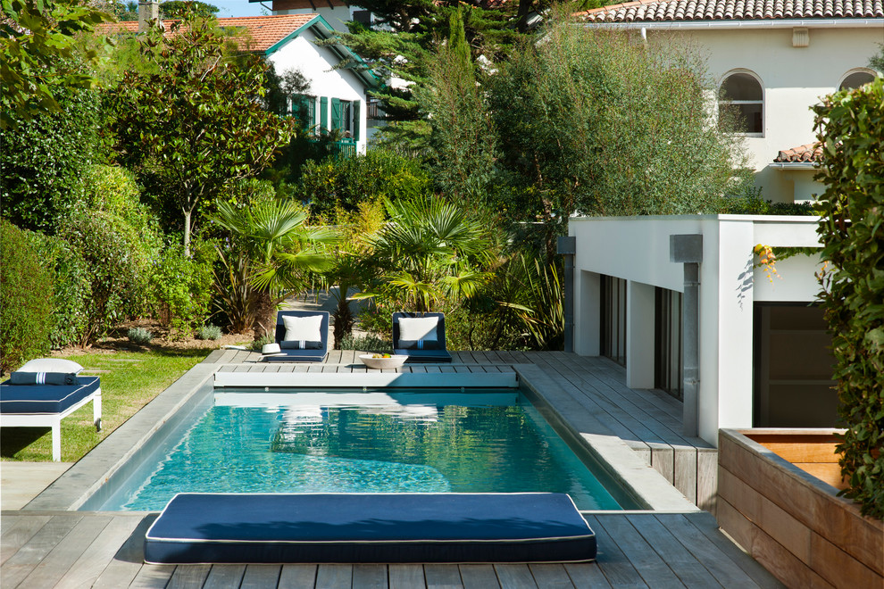 Inspiration pour une piscine arrière marine rectangle avec une terrasse en bois.