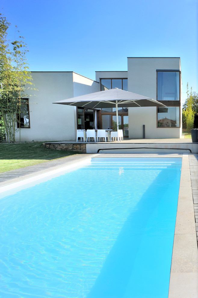 Foto de piscina actual grande rectangular en patio trasero con entablado