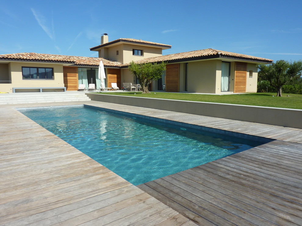 Cette image montre une piscine arrière méditerranéenne rectangle et de taille moyenne avec une terrasse en bois.
