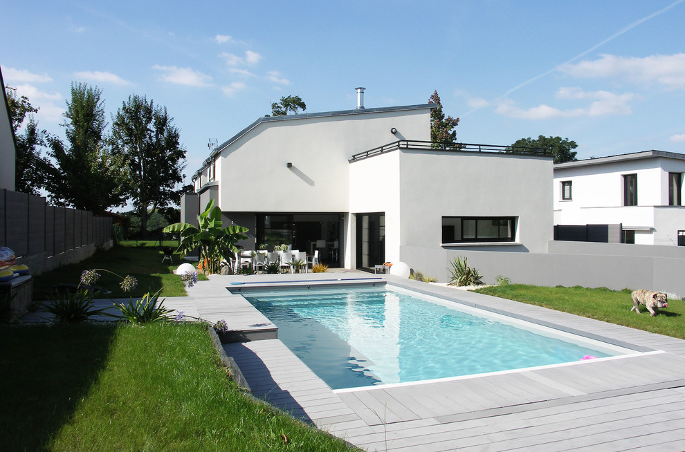 Imagen de piscinas y jacuzzis alargados actuales de tamaño medio rectangulares en patio trasero con entablado