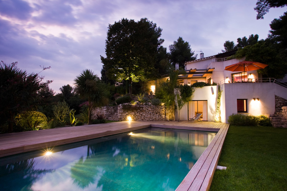 Modelo de piscina mediterránea grande rectangular en patio trasero con entablado