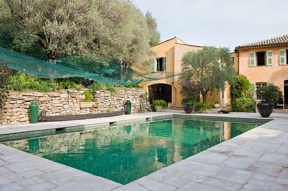 На фото: большой естественный, прямоугольный бассейн в средиземноморском стиле с покрытием из каменной брусчатки с