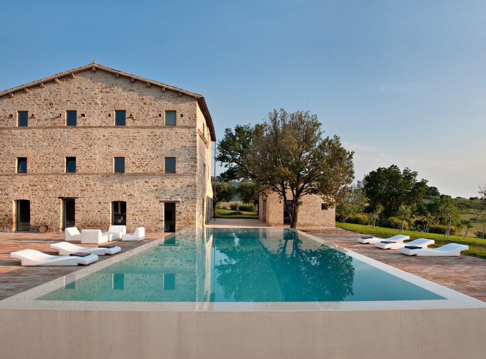 Diseño de piscina elevada mediterránea grande rectangular con adoquines de ladrillo