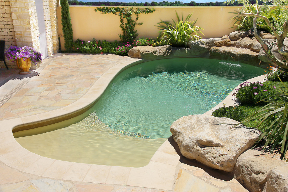 Cette photo montre une petite piscine nature sur mesure avec un point d'eau et des pavés en pierre naturelle.