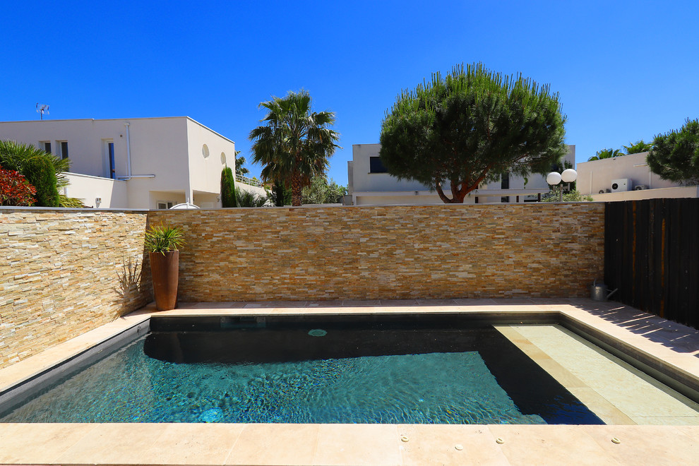 Immagine di una piccola piscina design rettangolare con pavimentazioni in pietra naturale