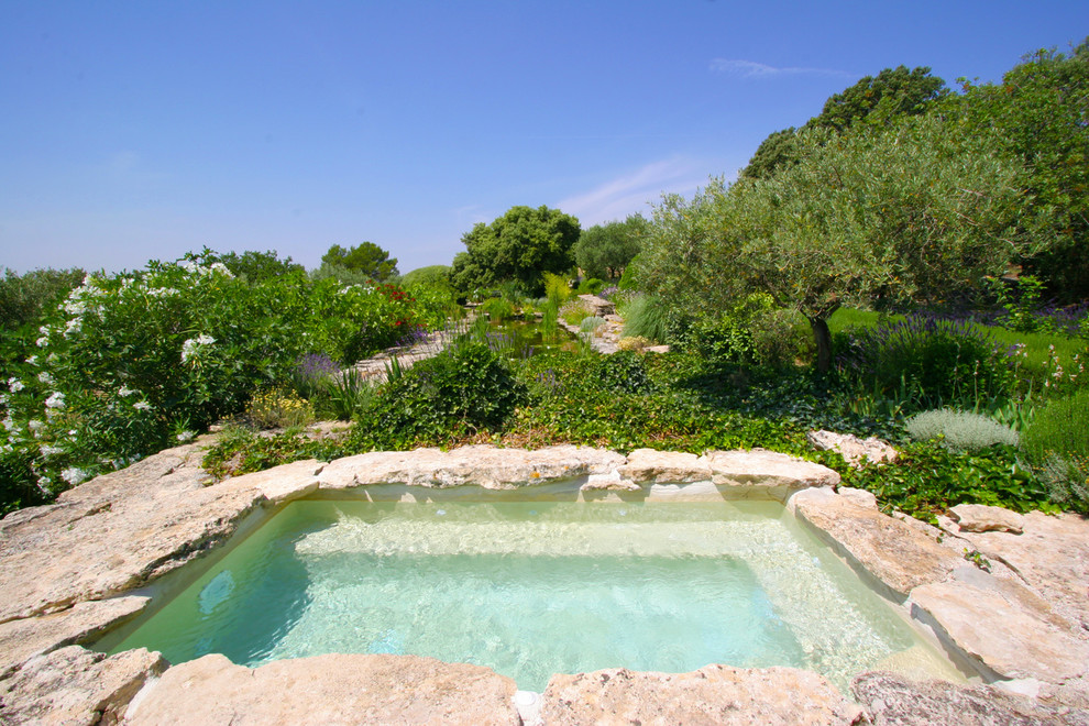Aménagement d'une piscine méditerranéenne rectangle avec un bain bouillonnant et des pavés en pierre naturelle.