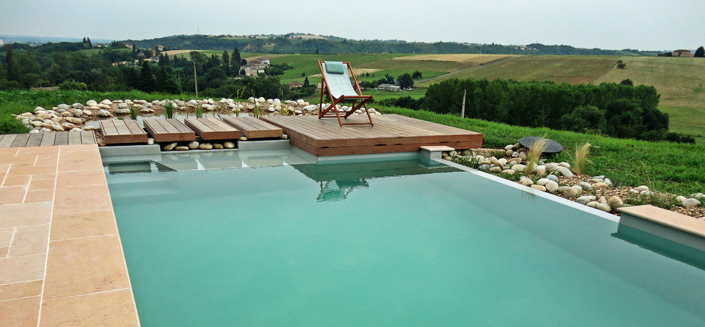 Immagine di una piscina naturale mediterranea rettangolare di medie dimensioni e dietro casa con piastrelle